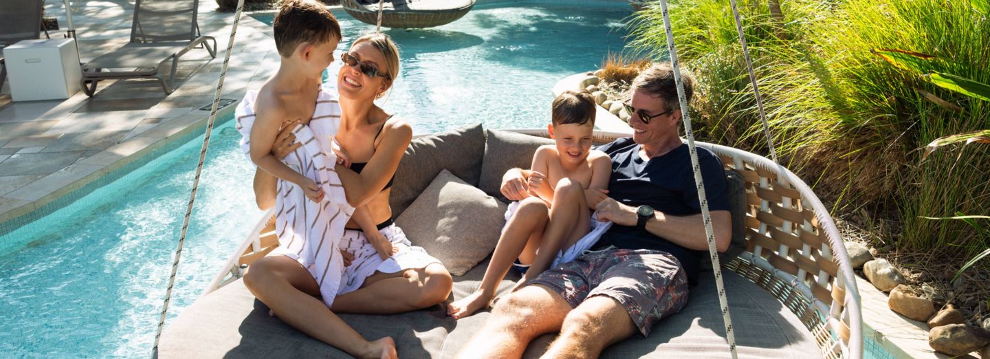 Family on hanging pool seat at Elements of Byron