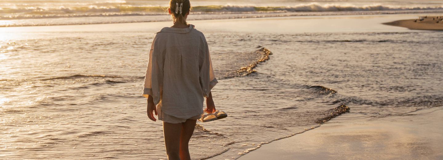 Woman on empty Belongil Beach outside Elements of Byron