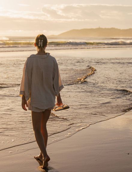 Woman on empty Belongil Beach outside Elements of Byron