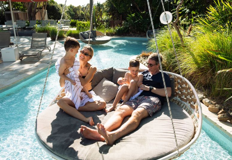 Family on hanging pool seat at Elements of Byron