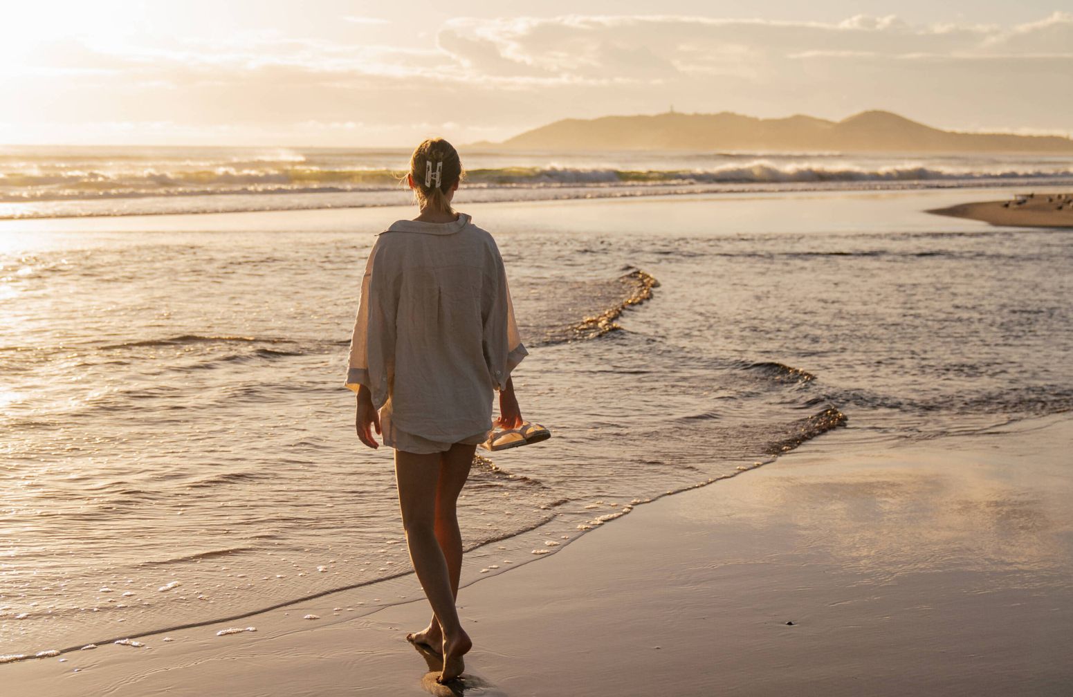 Woman on empty Belongil Beach outside Elements of Byron